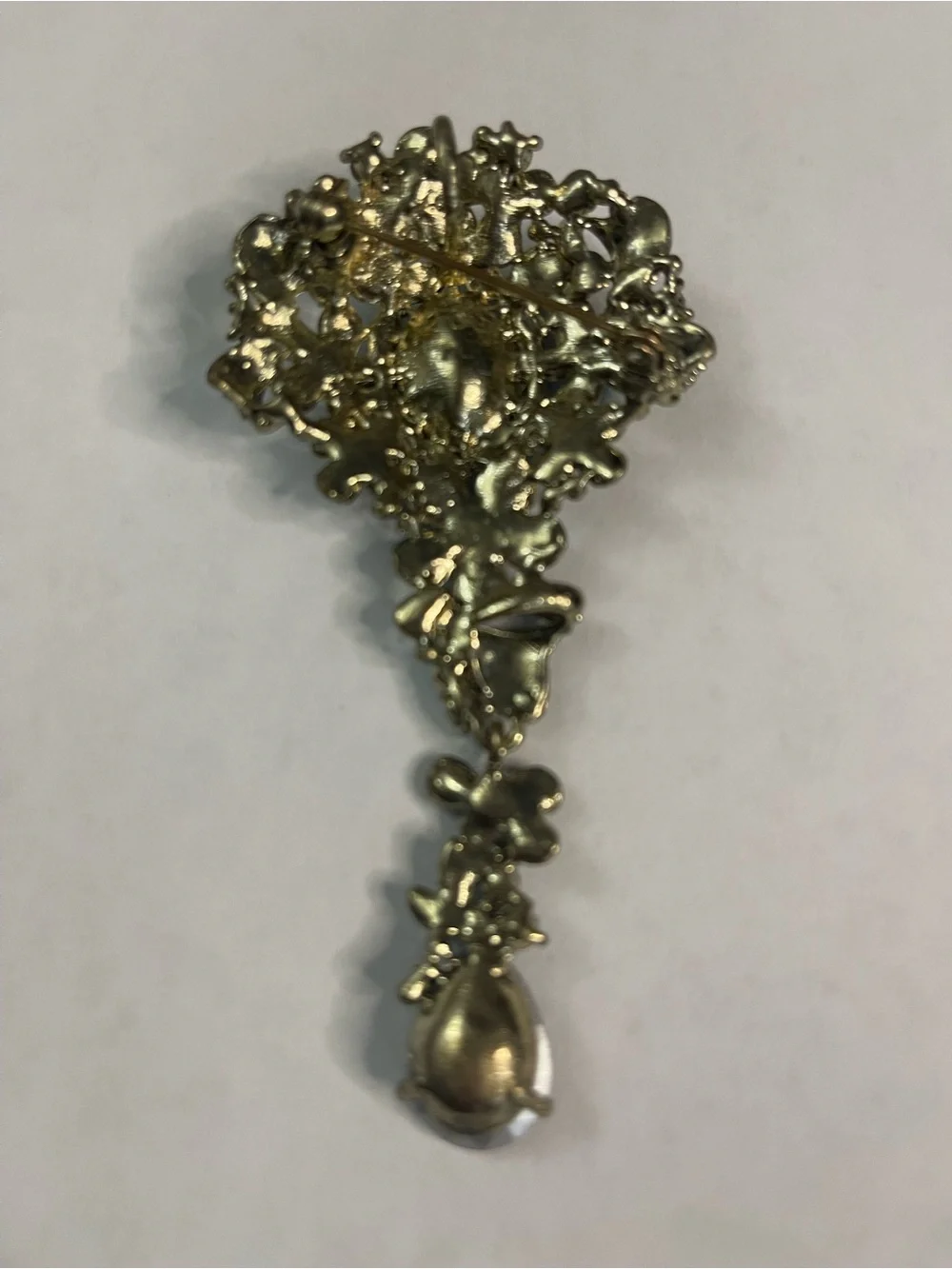 gold-tone teardrop pin featuring a central green crystal surrounded